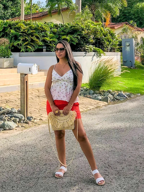 Woman wearing a white flowery top and shorts. 