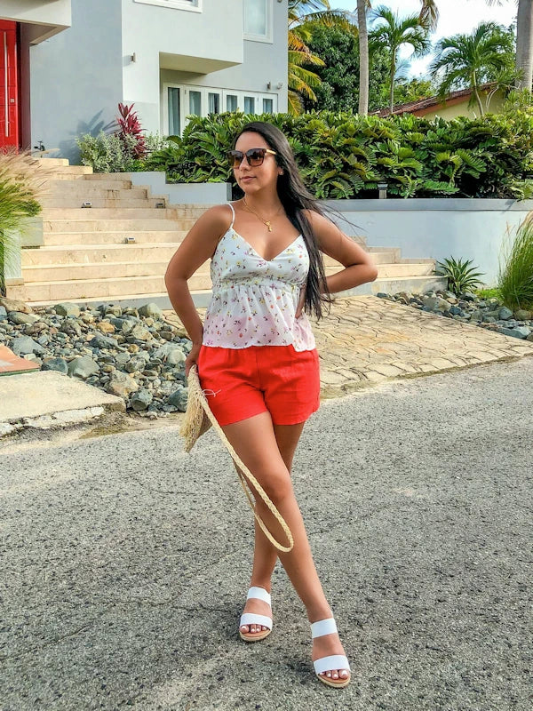 Woman wearing a floral peplum tank top and red shorts.
