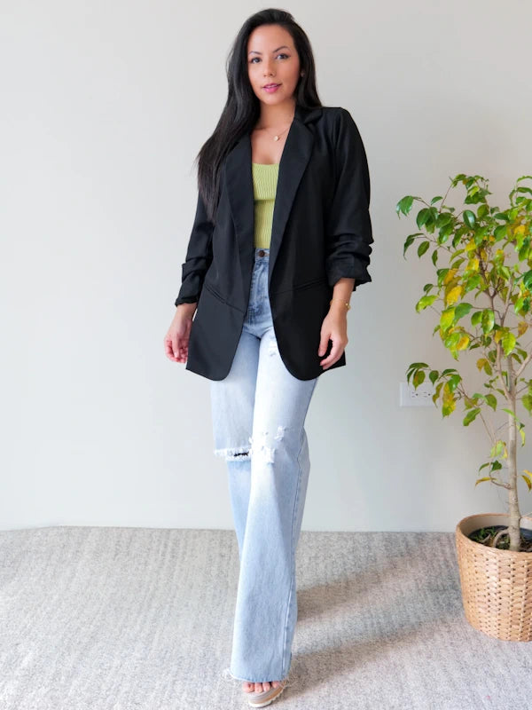 Woman wearing al ladies long blazer jacket in black and jeans with knee rips. 