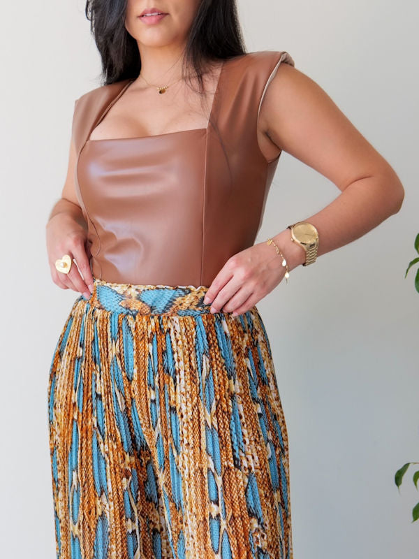 Woman wearing a sleeveless square neck bodysuit in faux leather. 